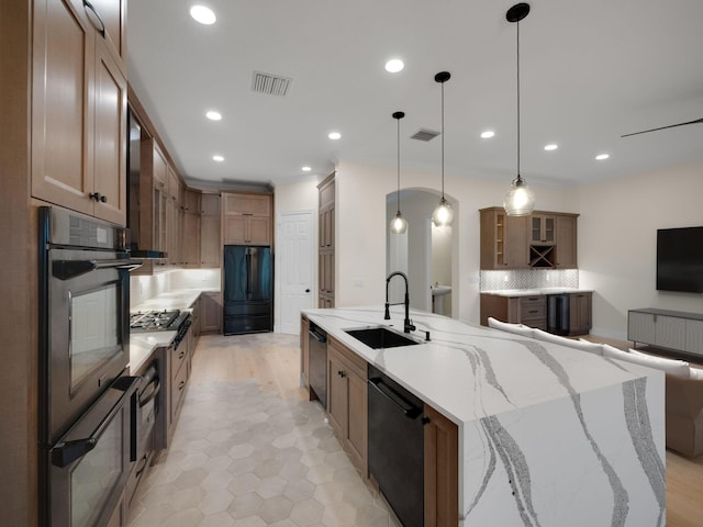 kitchen with light stone countertops, tasteful backsplash, stainless steel appliances, sink, and pendant lighting