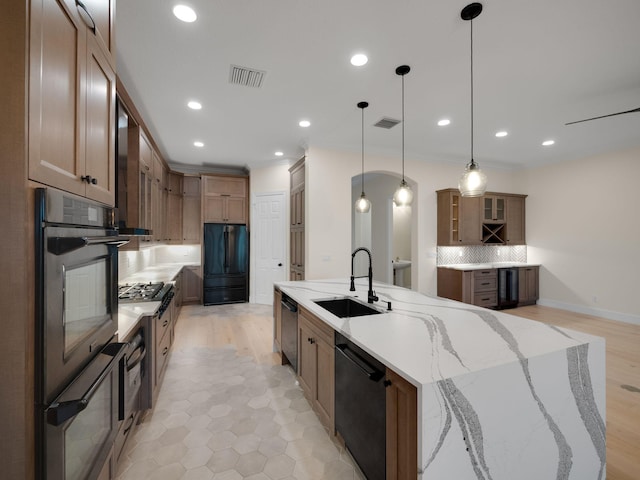 kitchen featuring sink, tasteful backsplash, light stone counters, pendant lighting, and appliances with stainless steel finishes