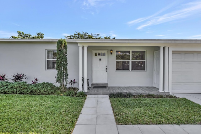 view of exterior entry with a garage and a yard