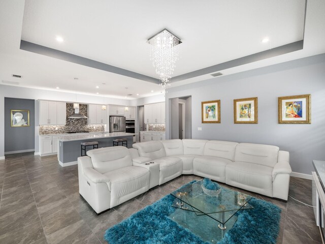 living room with a tray ceiling and a notable chandelier