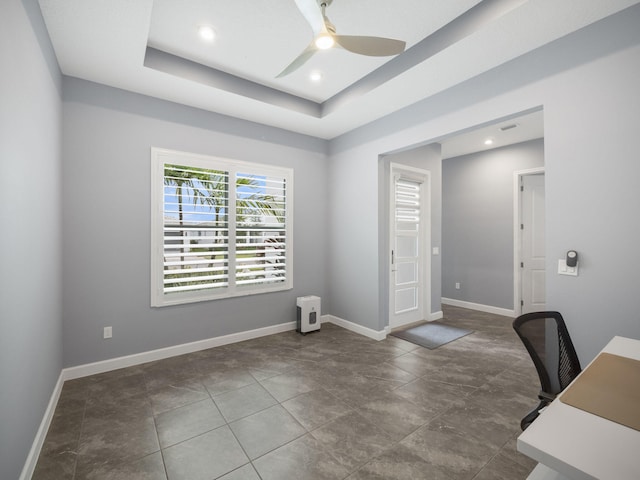 unfurnished office featuring a raised ceiling and ceiling fan