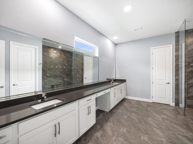 bathroom with tiled shower, a textured ceiling, and vanity