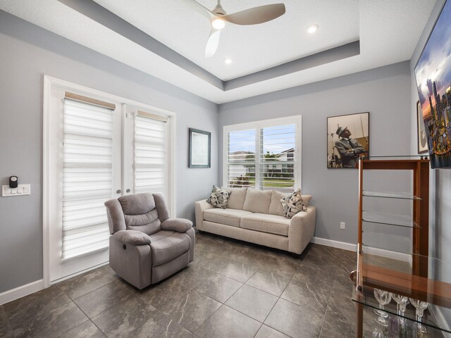 living room featuring a tray ceiling and ceiling fan