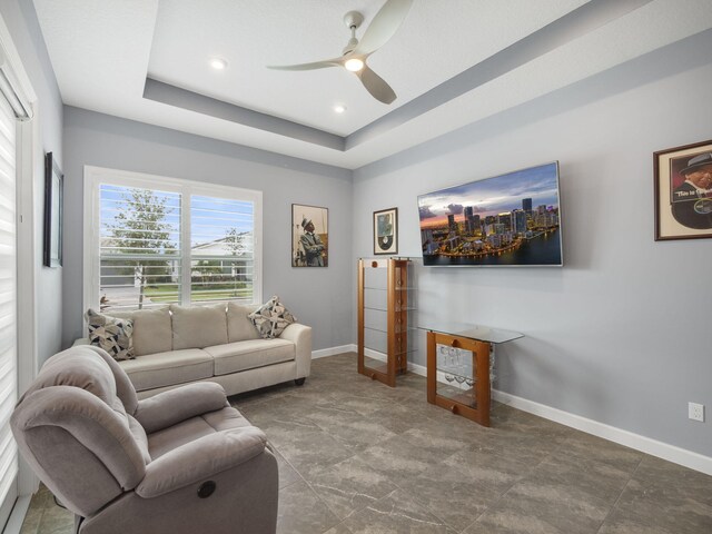 living room featuring ceiling fan and a raised ceiling