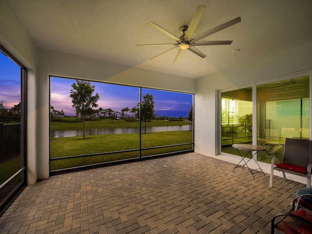 sunroom / solarium featuring a water view and ceiling fan