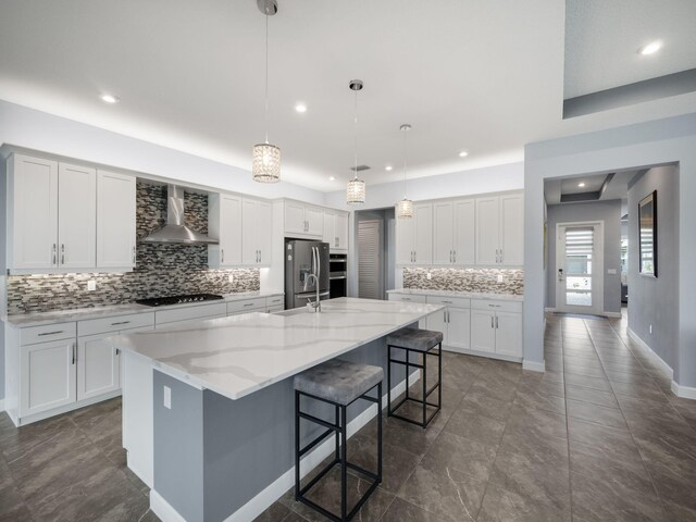 kitchen with stainless steel fridge with ice dispenser, white cabinets, wall chimney range hood, and black gas cooktop