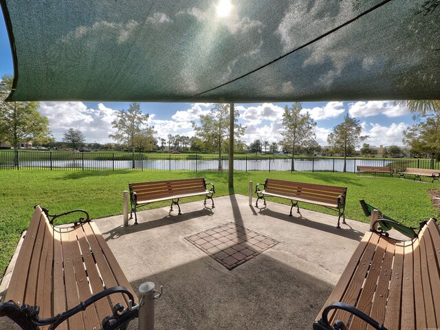 view of community with a lawn, a water view, and a patio