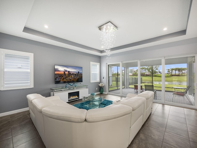 living room with a tray ceiling, tile patterned floors, and an inviting chandelier