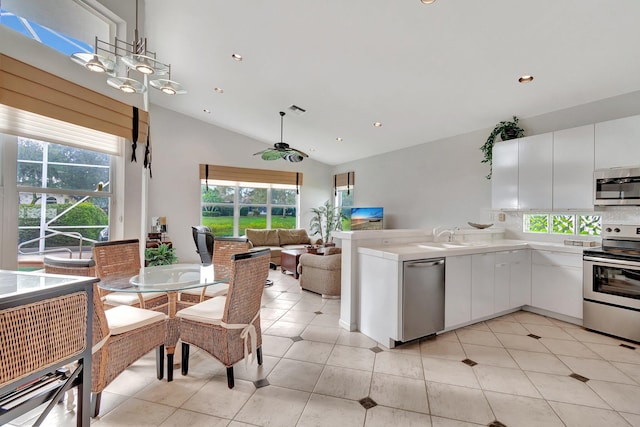 kitchen with white cabinetry, sink, stainless steel appliances, lofted ceiling, and light tile patterned floors