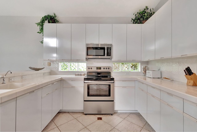 kitchen with white cabinets, a healthy amount of sunlight, sink, and stainless steel appliances