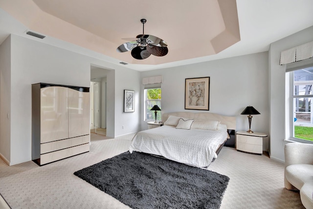 carpeted bedroom with a tray ceiling and ceiling fan