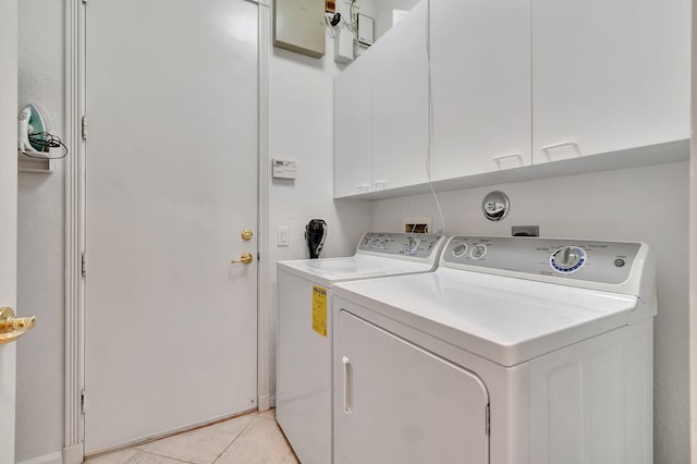 washroom featuring washer and clothes dryer, cabinets, and light tile patterned floors