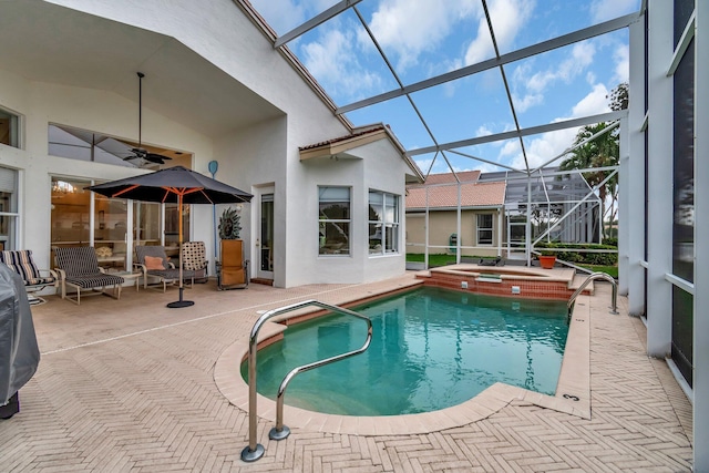 view of swimming pool featuring an in ground hot tub, a patio, glass enclosure, and ceiling fan