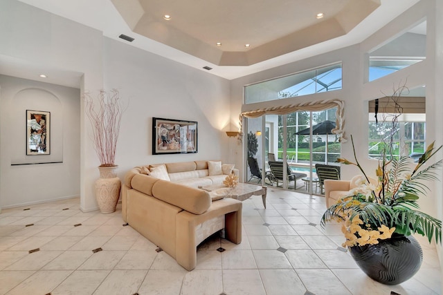 tiled living room featuring a high ceiling and a tray ceiling