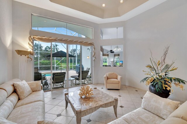 living room with ceiling fan, light tile patterned flooring, and a high ceiling