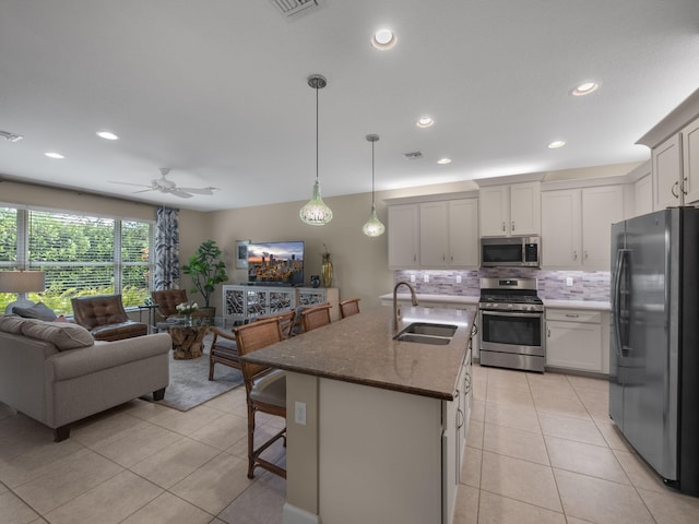 kitchen with pendant lighting, a center island with sink, sink, ceiling fan, and appliances with stainless steel finishes