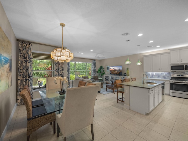 tiled dining space with sink and ceiling fan with notable chandelier