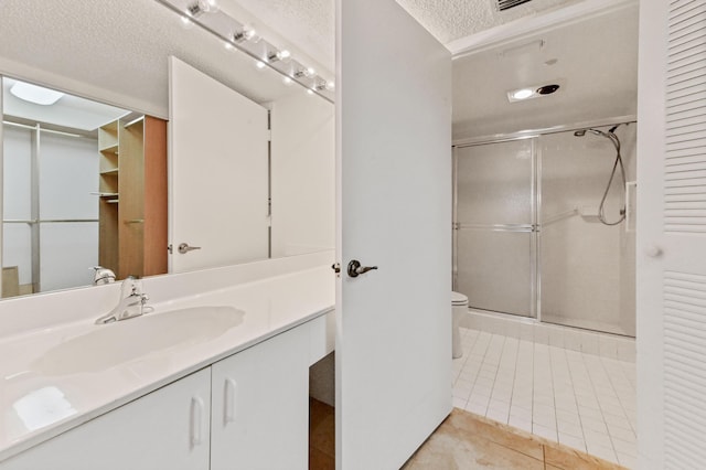 bathroom with tile patterned floors, a shower with door, vanity, and a textured ceiling