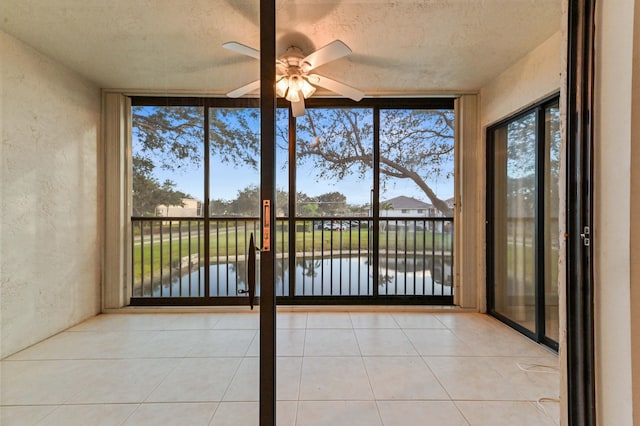 unfurnished sunroom with a water view, ceiling fan, and a healthy amount of sunlight