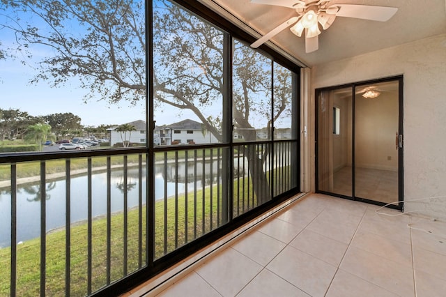 unfurnished sunroom featuring ceiling fan, plenty of natural light, and a water view