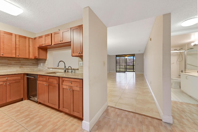 kitchen with sink, light stone countertops, a textured ceiling, light tile patterned floors, and tasteful backsplash