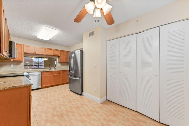 kitchen featuring appliances with stainless steel finishes, tasteful backsplash, a textured ceiling, ceiling fan, and sink