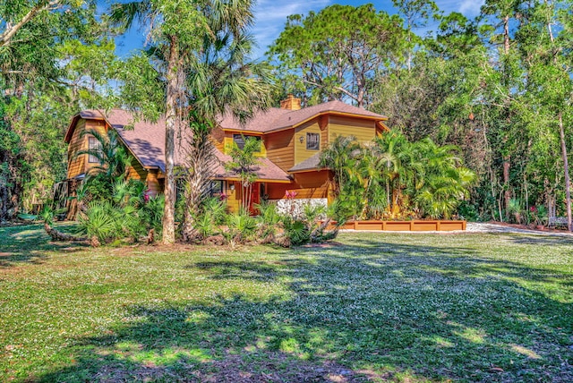 view of front of home featuring roof with shingles, a chimney, and a front lawn