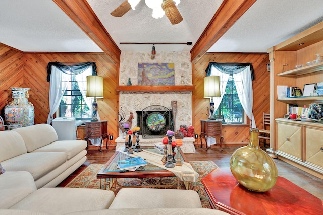 living room with hardwood / wood-style flooring, plenty of natural light, a textured ceiling, and a stone fireplace