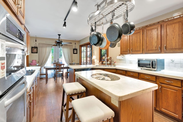 kitchen featuring ceiling fan, hardwood / wood-style floors, a center island, stainless steel appliances, and a breakfast bar area