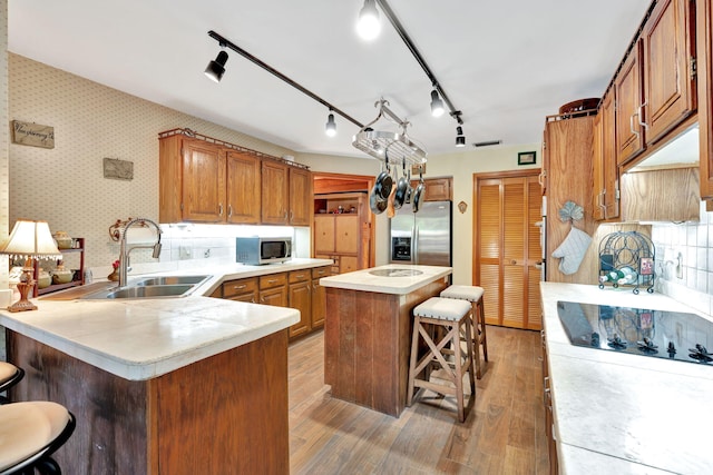 kitchen featuring stainless steel appliances, backsplash, a kitchen island, a breakfast bar, and sink