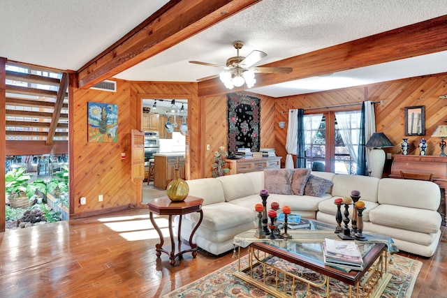 living room featuring beam ceiling, visible vents, ceiling fan, a textured ceiling, and wood finished floors