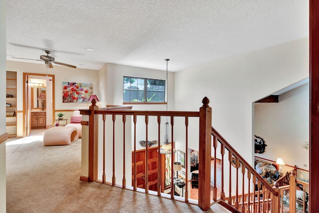 staircase featuring ceiling fan, carpet, and a textured ceiling