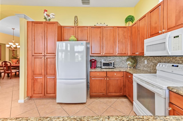 kitchen featuring hanging light fixtures, a notable chandelier, white appliances, decorative backsplash, and light tile patterned floors