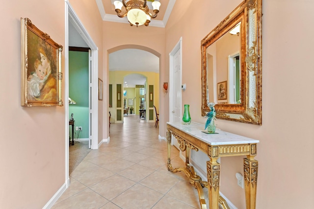 hallway featuring crown molding, light tile patterned floors, and an inviting chandelier