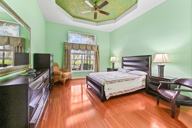 bedroom featuring wood-type flooring, a raised ceiling, and ceiling fan