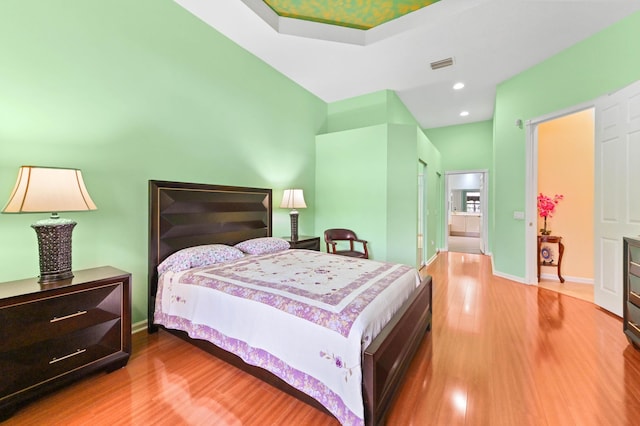 bedroom with ensuite bathroom and hardwood / wood-style floors