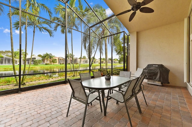 sunroom / solarium featuring a water view and ceiling fan