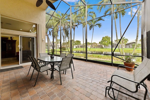 sunroom / solarium featuring ceiling fan and a water view