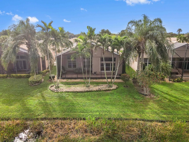 rear view of property with a lawn and glass enclosure