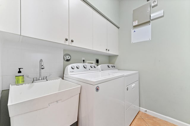 laundry area featuring washer and dryer, sink, light tile patterned floors, and cabinets