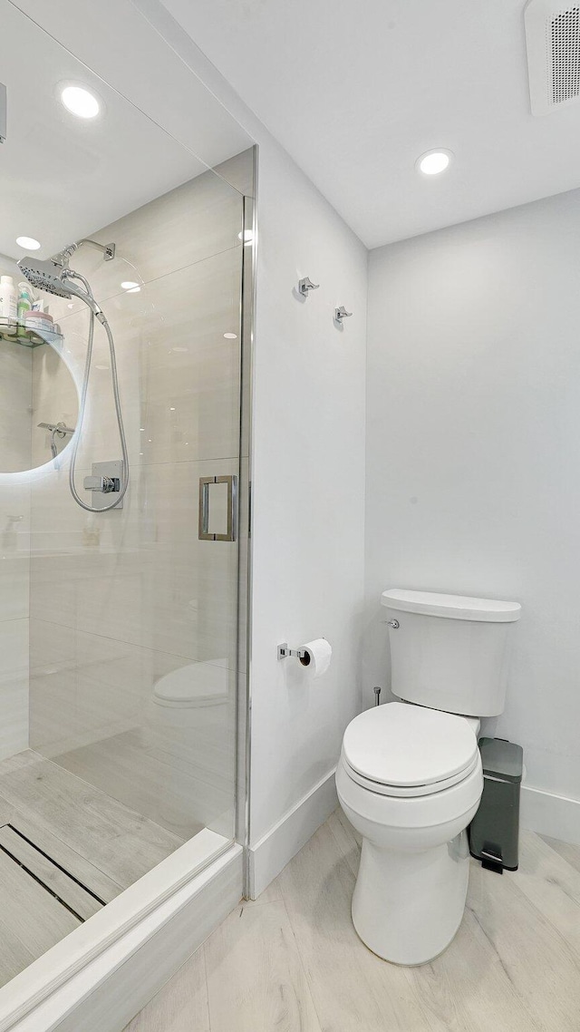 bathroom with toilet and a shower with door