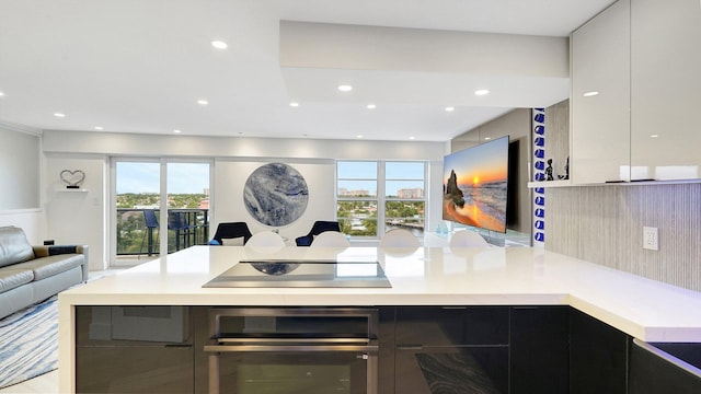 kitchen with white cabinets, black electric cooktop, oven, and a healthy amount of sunlight