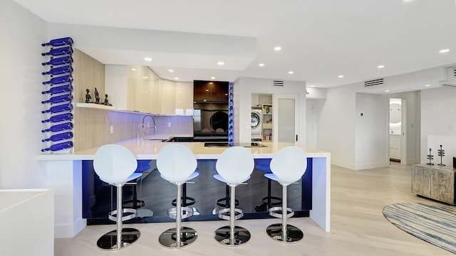 kitchen featuring sink, backsplash, kitchen peninsula, stovetop, and a breakfast bar