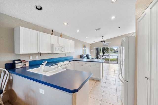 kitchen featuring sink, kitchen peninsula, vaulted ceiling, white appliances, and white cabinets