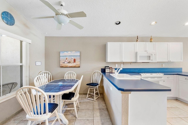 kitchen with white cabinets, light tile patterned floors, white appliances, and sink