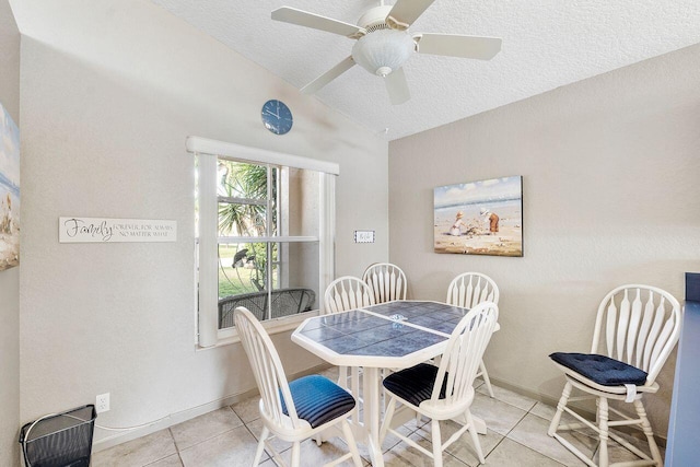 dining space with lofted ceiling, ceiling fan, light tile patterned floors, and a textured ceiling