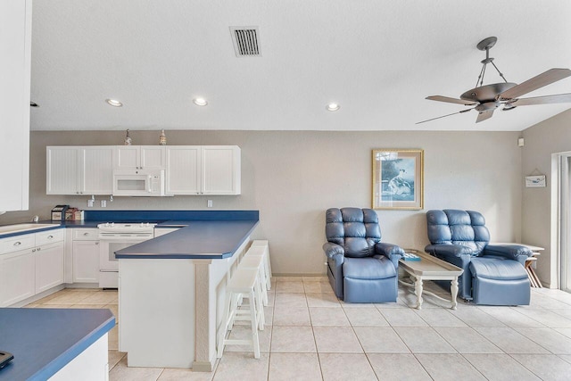 kitchen with stove, a kitchen breakfast bar, ceiling fan, light tile patterned floors, and white cabinets