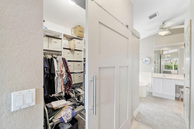 bathroom featuring a tub, ceiling fan, lofted ceiling, a textured ceiling, and vanity