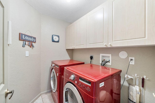 clothes washing area featuring washer and dryer, light tile patterned floors, cabinets, and a textured ceiling