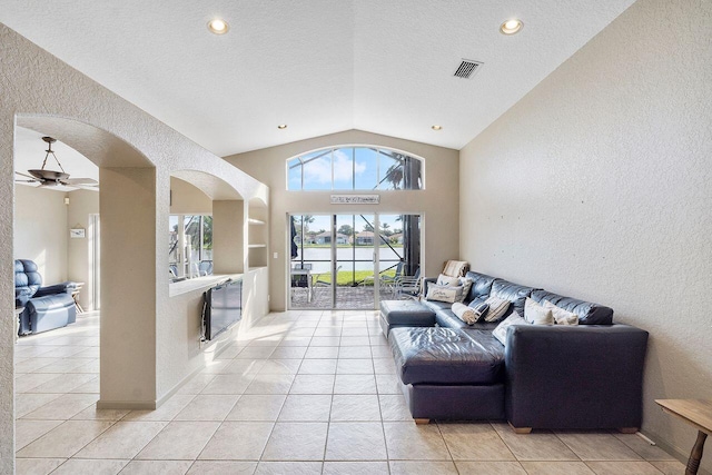 living room with built in shelves, ceiling fan, a textured ceiling, lofted ceiling, and light tile patterned floors